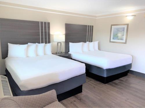 una habitación de hotel con 2 camas y una silla en Summerfield Inn Fresno Yosemite en Fresno