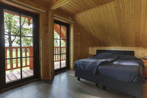 a bedroom with a bed in a room with windows at Houten villa Tine in Den Ham
