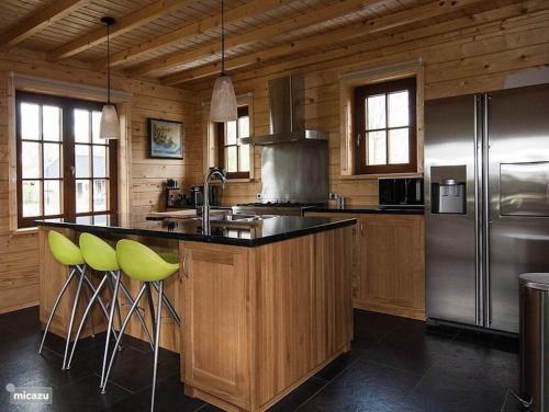 a kitchen with a island with green bar stools at Houten villa Tine in Den Ham