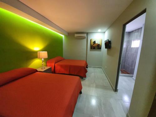 a hotel room with two beds and a green wall at Hotel HC Express in Monterrey
