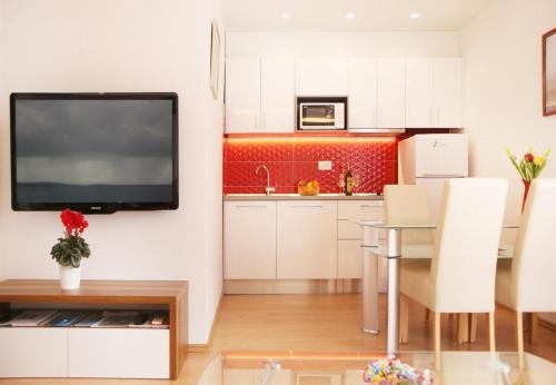 a kitchen with a table and a television on a wall at Apartment JoviZ - 20m from the sea in Makarska