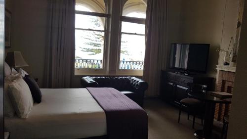 a hotel room with a bed, tv and a window at Largs Pier Hotel in Adelaide