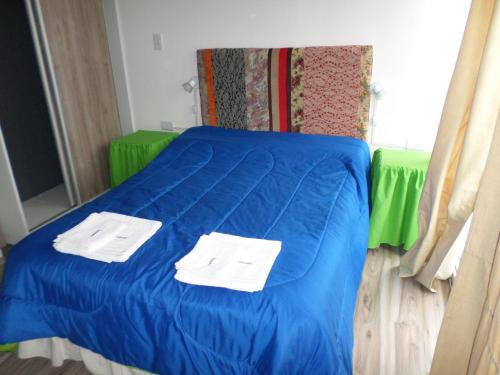 a bed with blue sheets and white towels on it at departamento salta argentina in Salta