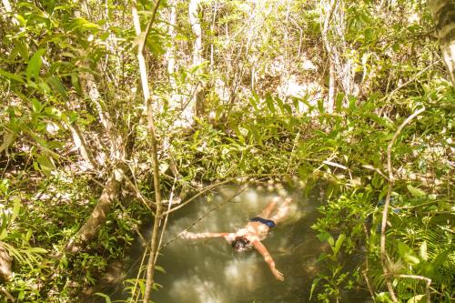 a man swimming in a river in the jungle at Raizando Ecologia Humana in Alto Paraíso de Goiás