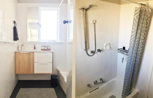 a bathroom with a shower and a sink and a tub at Quick Stroll To The City in Geraldton