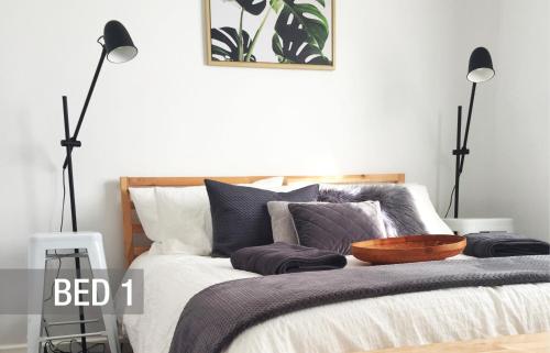 a bedroom with a bed with two floor lamps at Quick Stroll To The City in Geraldton