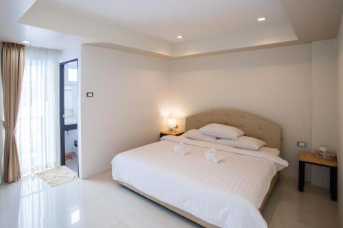 a bedroom with a white bed with two white pillows at Le Neuf Nakorn Lampang in Lampang