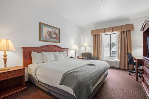 a hotel room with a bed, chair, and nightstand at Stay USA Hotel and Suites in Hot Springs