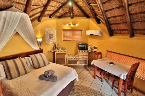 a bedroom with a bed and a table at Manzini Chalets in Marloth Park