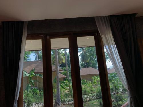 two windows with curtains in a room with at Thiwson Beach Resort - SHA Extra Plus in Ko Yao Yai