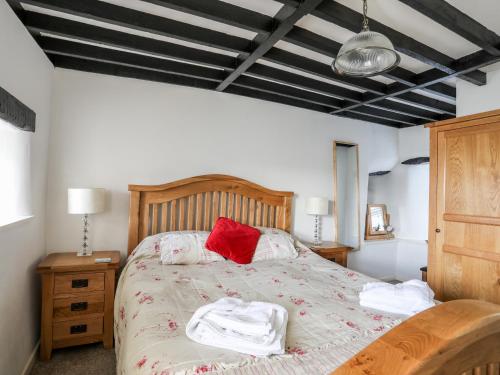 a bedroom with a bed with red pillows on it at Farm Cottage in Cemaes Bay
