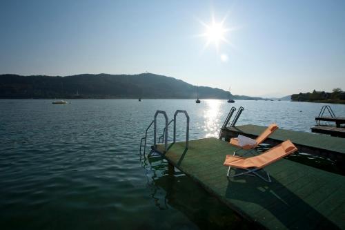 a dock with two chairs on the water at St. Oswalderhof in Pörtschach am Wörthersee