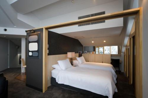 a bedroom with two beds and a large window at The Ridge Hakuba Hotel & Apartments in Hakuba