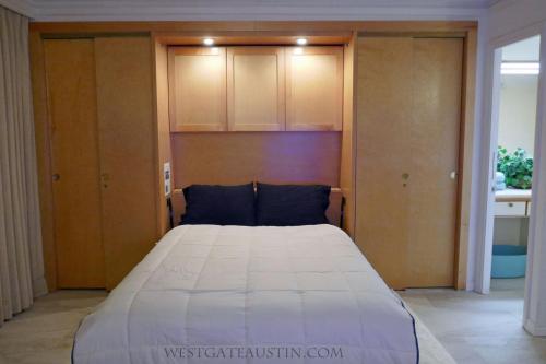 1 dormitorio con 1 cama blanca grande y armarios de madera en WestgateAustin - Downtown Austin, Capitol Next Door, 30 Day Rental, en Austin