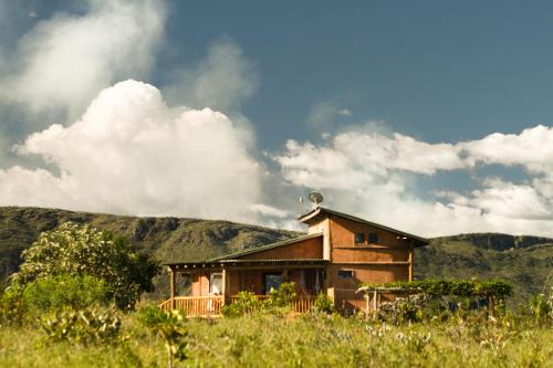a house in a field with mountains in the background at Raizando Ecologia Humana in Alto Paraíso de Goiás