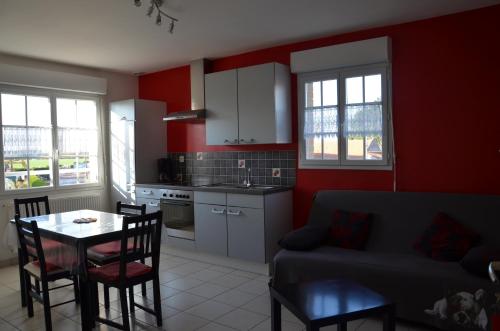 a kitchen and living room with a table and a couch at La Résidence des Fleurs in Lecelles