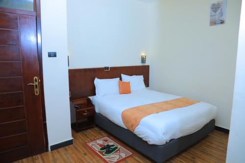阿克苏姆Obelisk Hotel Axum的卧室里有一张床，床单是白色的，枕头是橙色的