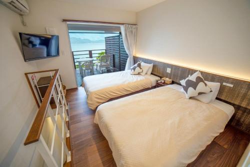 two beds in a room with a balcony at Native Sea Amami Adan On The Beach in Tatsugo