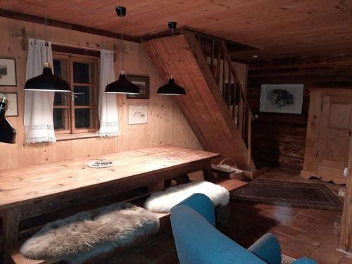 a living room with a wooden table and a staircase at Almhütte Chalet HIRSCHFISCH in Bodensdorf