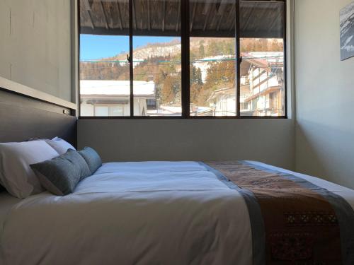 a bed in a bedroom with a large window at Shiro Nozawa in Nozawa Onsen