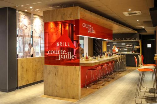 a restaurant with a counter with a bar with stools at Ibis Saint-Genis-Pouilly Genève in Saint-Genis-Pouilly
