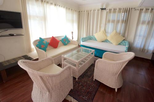 a living room with wicker chairs and a couch at Magpie Retreat in Bhīm Tāl