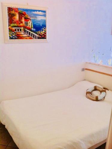 a white bed with a picture on the wall at “L’alcova delle Sirene” in Bergeggi