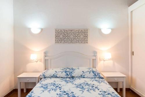 una camera da letto con un letto bianco con fiori blu di Chalet Cerca de la Playa a Cala'n Bosch