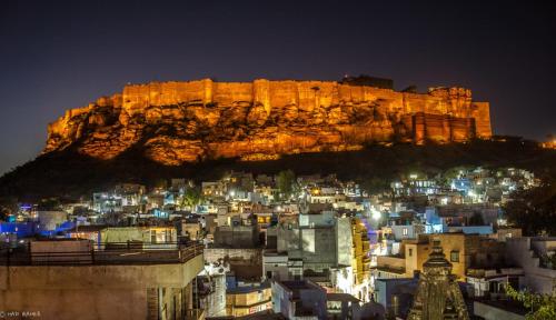 a city lit up at night in front of a mountain at The Blue House in Jodhpur