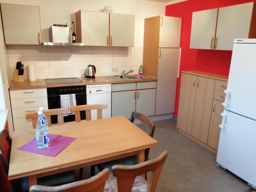a small kitchen with a wooden table and a refrigerator at Moderne ganze Ferienwohnung 1km zum FunPark und nur 15 Minuten nach Nürnberg in Zirndorf