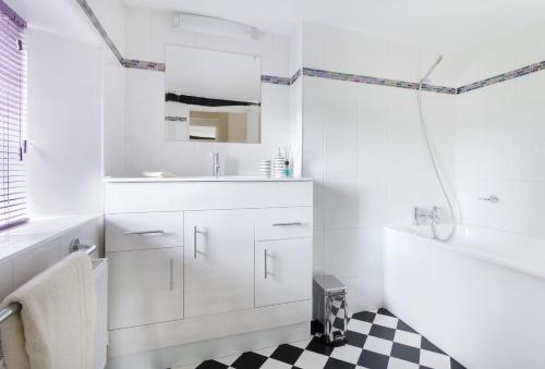 La salle de bains est pourvue de placards blancs et d'un sol en damier noir et blanc. dans l'établissement Riverside House, à Broom