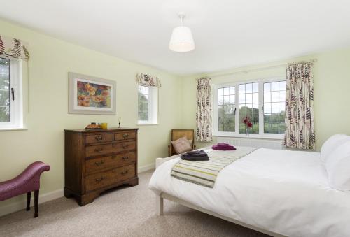 a bedroom with a bed and a dresser and windows at Riverside House in Broom