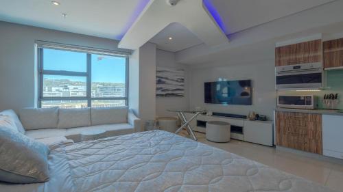 a bedroom with a bed and a couch and a tv at Pearls Studio Inland Facing - Self Catering in Durban