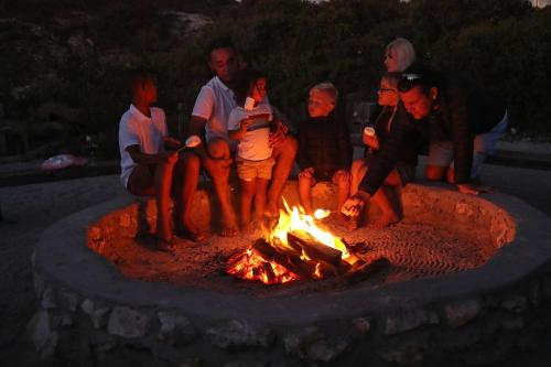 a group of people around a fire pit at night at Blue Bay Lodge in Saldanha