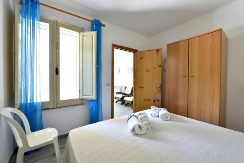 ein Schlafzimmer mit einem Bett, einem Stuhl und einem Fenster in der Unterkunft Casa Cala Sisine in Santa Maria Navarrese