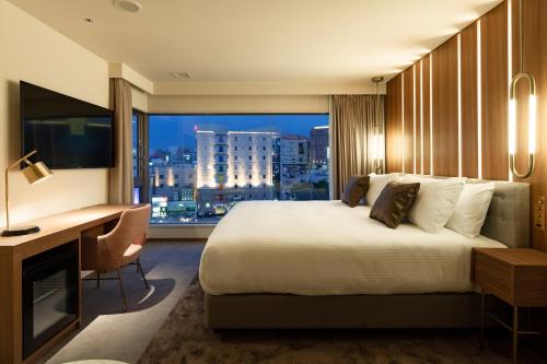 a hotel room with a bed and a desk and a window at The OneFive Villa Fukuoka in Fukuoka