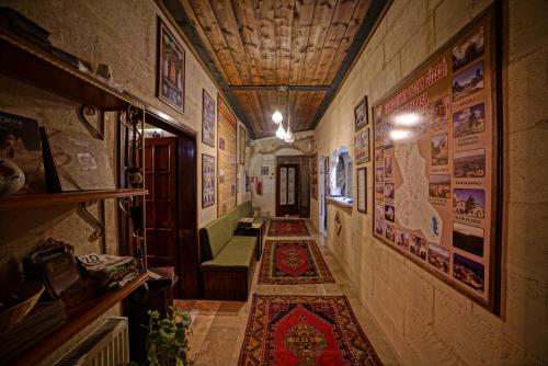 a hallway with posters on the walls and a rug at Jerveni Cave Hotel in Mustafapaşa