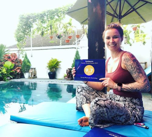 a woman sitting on a surfboard next to a swimming pool at Sunny Riverside Homestay in Hoi An