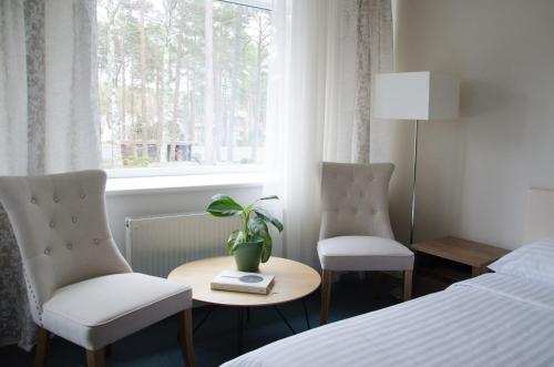 Habitación de hotel con 2 sillas, mesa y ventana en Pine Resort, en Saulkrasti
