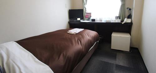 a small bedroom with a bed and a window at Takamatsu City Hotel in Takamatsu