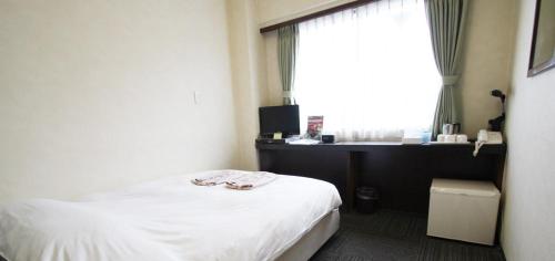 a bedroom with a bed and a desk and a window at Takamatsu City Hotel in Takamatsu