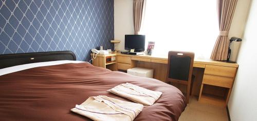 a bedroom with a bed and a desk with a computer at Takamatsu City Hotel in Takamatsu