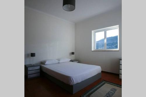 ein weißes Schlafzimmer mit einem Bett und einem Fenster in der Unterkunft Douro Valley - Casa do Campo Resende in Covelas