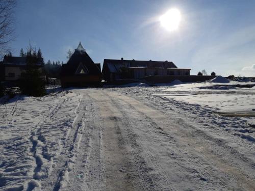 a dirt road with footprints in the snow in front of a house at Khatky Na Penkakh in Vorokhta