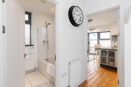 a bathroom with a shower and a clock on the wall at City Retreat, 2 Bed House with Cloudstream Hot Tub in Cardiff