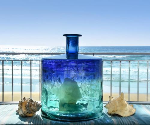 a blue glass bottle sitting on a table near the beach at Hotel Aurora in Sperlonga