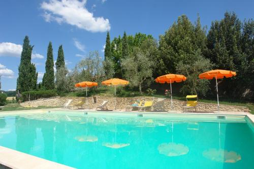 a swimming pool with orange umbrellas and chairs and tables at Ginestra in Poggibonsi