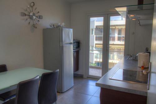 Il comprend une cuisine équipée d'un réfrigérateur et d'une table avec des chaises. dans l'établissement BEL APPARTEMENT PROCHE PLAGE ET CENTRE VILLE, à Cannes