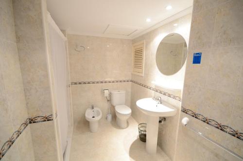 een badkamer met een toilet, een wastafel en een spiegel bij Hostal Mayol in Santa Eularia des Riu