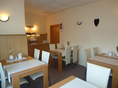 a dining room with tables and white chairs at Pension Thaler Hof in Thale
